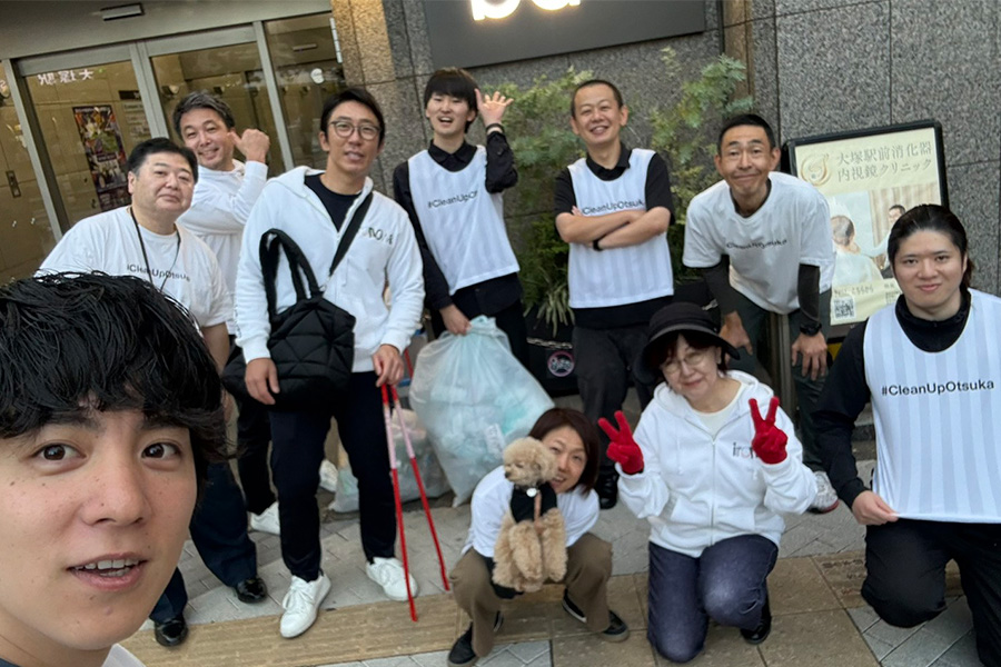 ビルの前で集合写真を撮る白いパーカーやビブスを着用した人々