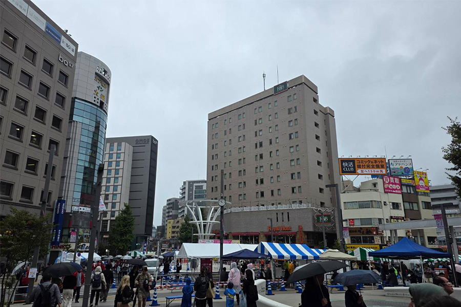 駅前の広場にたくさんのテントが配置されている。天候は曇り。