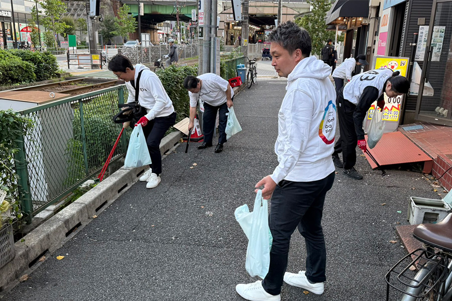 白いパーカーを着てゴミ拾いをする人々
