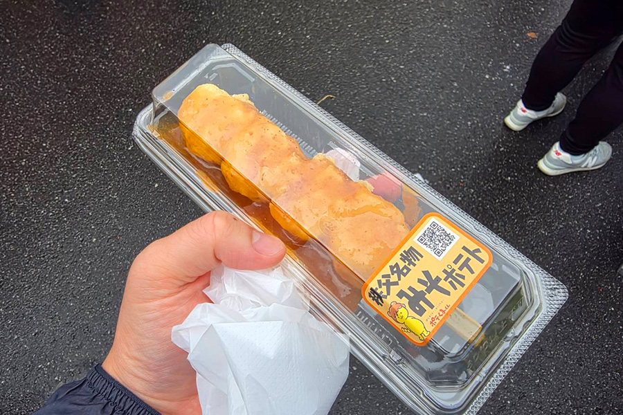 プラスチックの容器が入ったみそポテトを手に持つ様子。