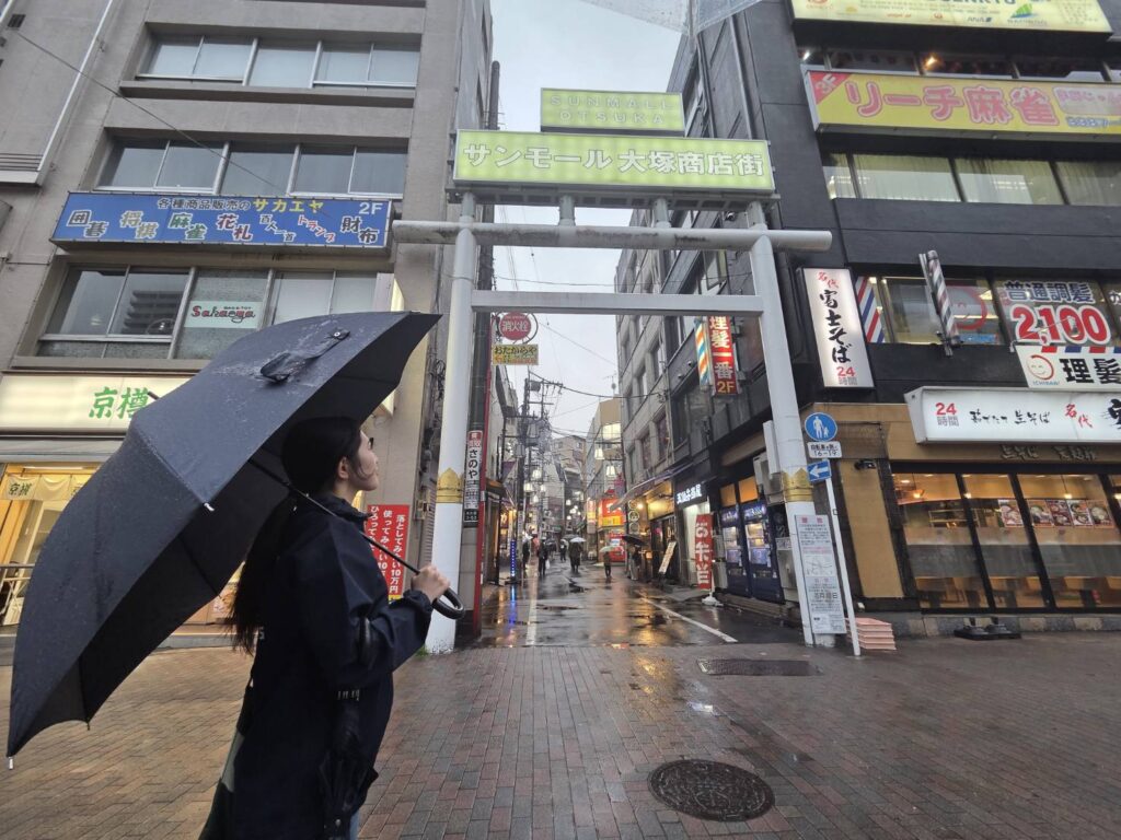 商店街の看板の前に立つ女性