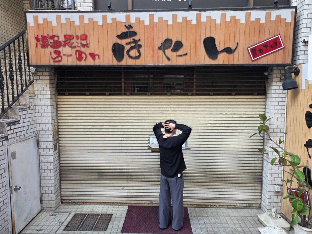 シャッターのしまったお店の前で立ち尽くす成人男性