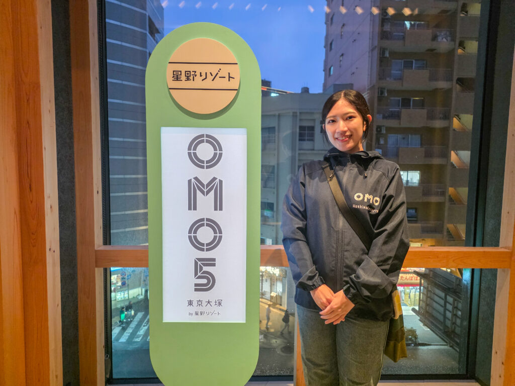 縦長の看板の横に立つ女性