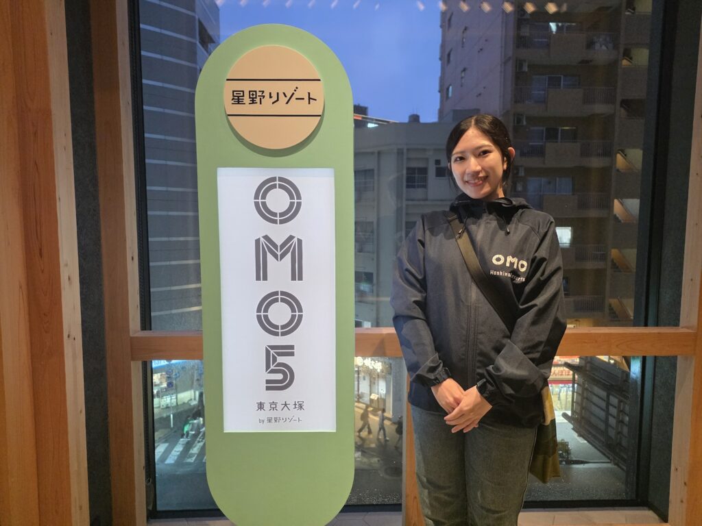 縦長の看板の横に立つ女性