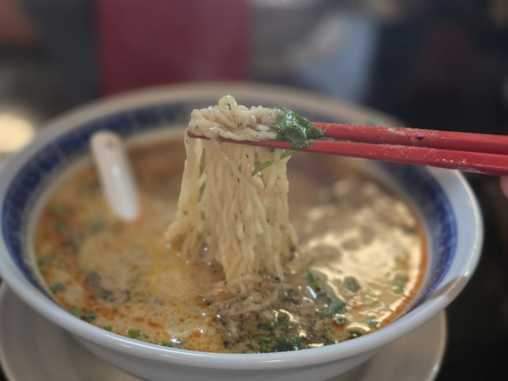 担々麺を赤い橋で持つ